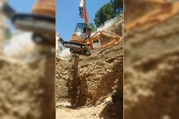 Grúa bajando excavadora en Agujero 
